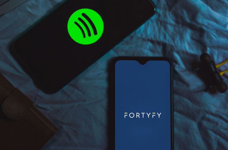 Smartphone showing the FORTYFY logo next to a phone with Spotify: how to switch music distributors without losing streams
